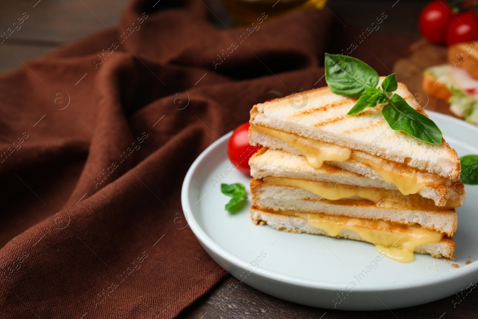 Photo of Pieces of toasted bread with melted cheese and basil on table