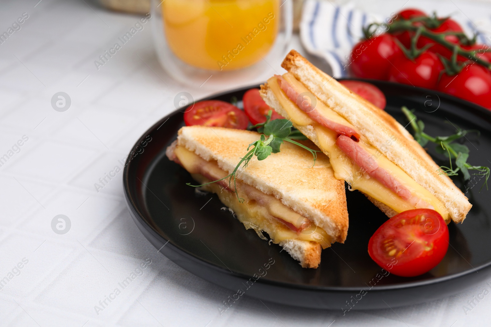 Photo of Pieces of toasted bread with melted cheese, ham and tomatoes on white tiled table