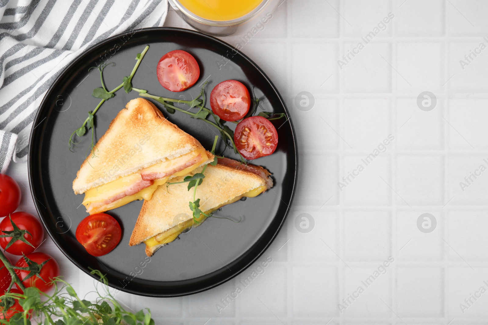 Photo of Pieces of toasted bread with melted cheese, ham and tomatoes on white tiled table, top view. Space for text