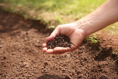 Photo of Woman holding pile of soil outdoors, closeup. Space for text