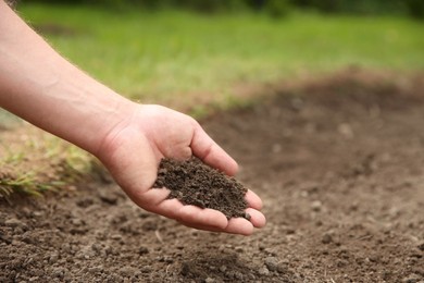 Woman holding pile of soil outdoors, closeup. Space for text