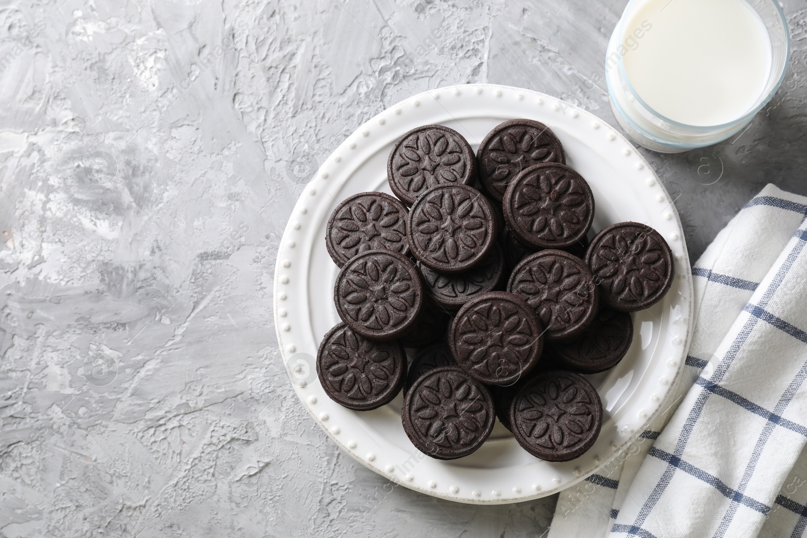 Photo of Tasty sandwich cookies and milk on light grey table, top view. Space for text