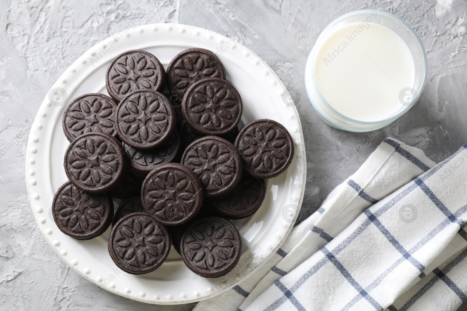 Photo of Tasty sandwich cookies and milk on light grey table, top view