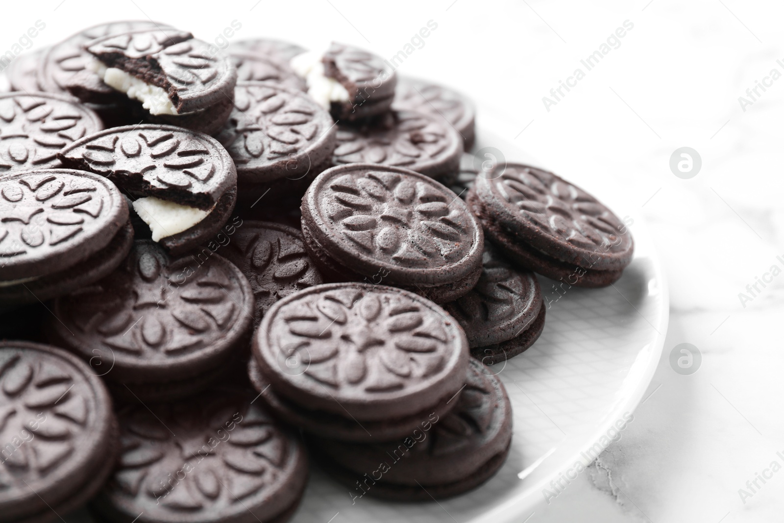 Photo of Tasty sandwich cookies on white marble table, closeup