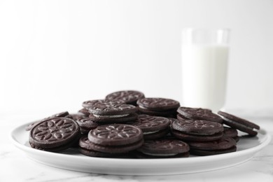 Tasty sandwich cookies and milk on white marble table