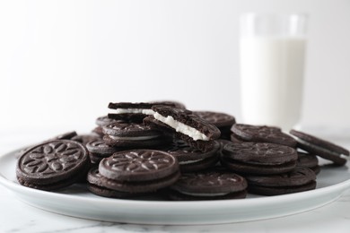 Photo of Tasty sandwich cookies and milk on white marble table