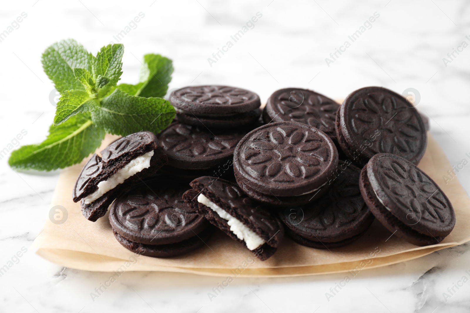 Photo of Tasty sandwich cookies and mint on white marble table