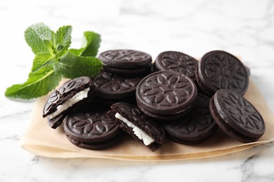 Tasty sandwich cookies and mint on white marble table