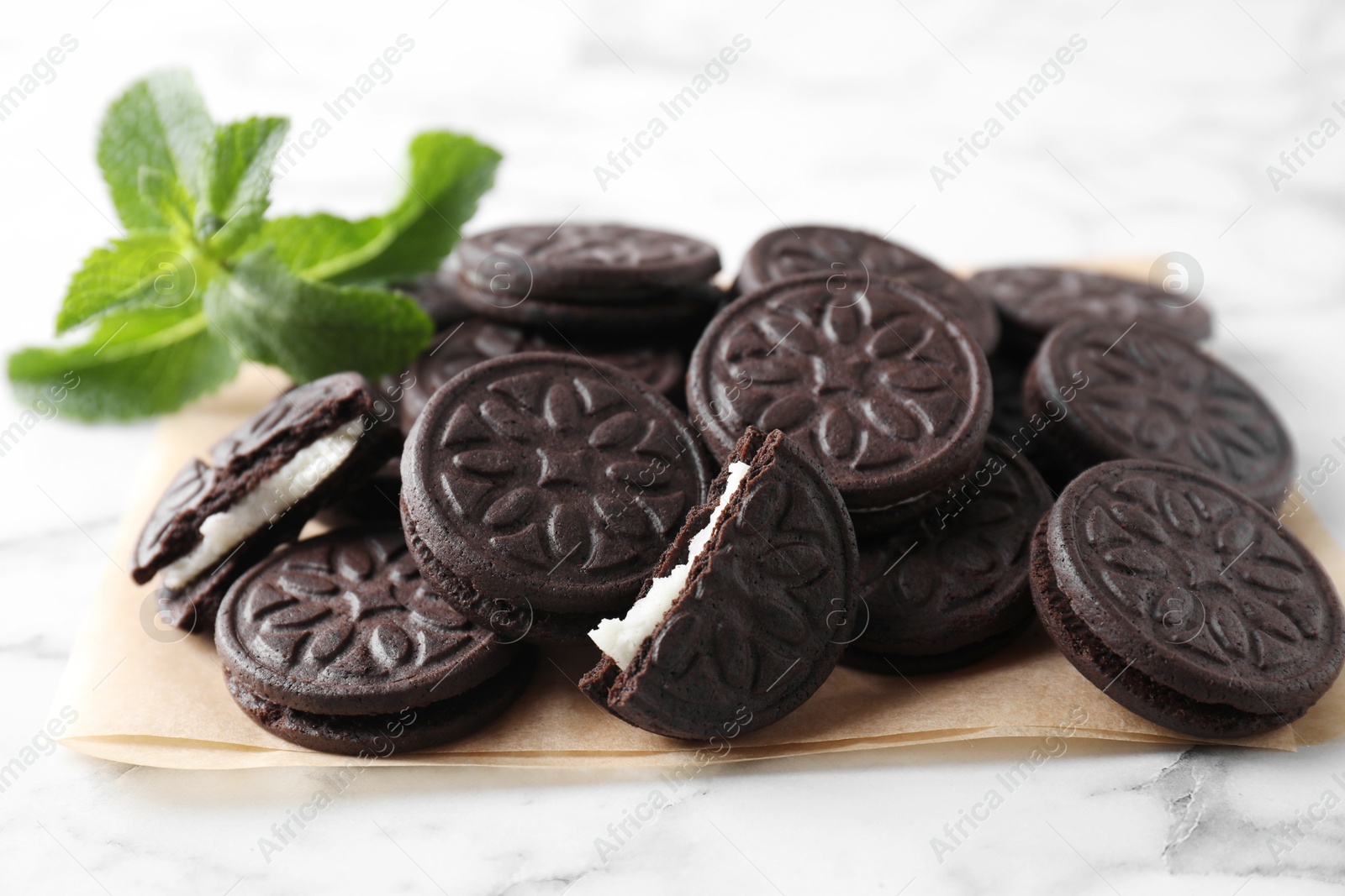 Photo of Tasty sandwich cookies and mint on white marble table