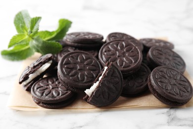 Tasty sandwich cookies and mint on white marble table