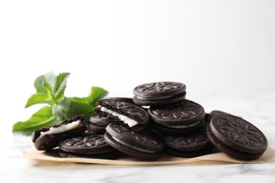 Photo of Tasty sandwich cookies and mint on white marble table