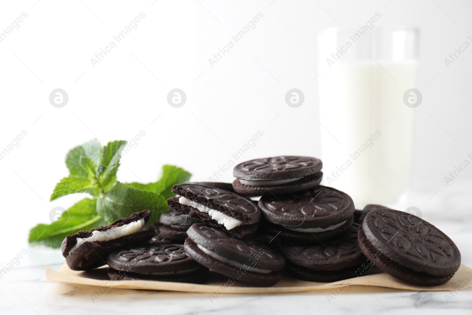 Photo of Tasty sandwich cookies and mint on white marble table