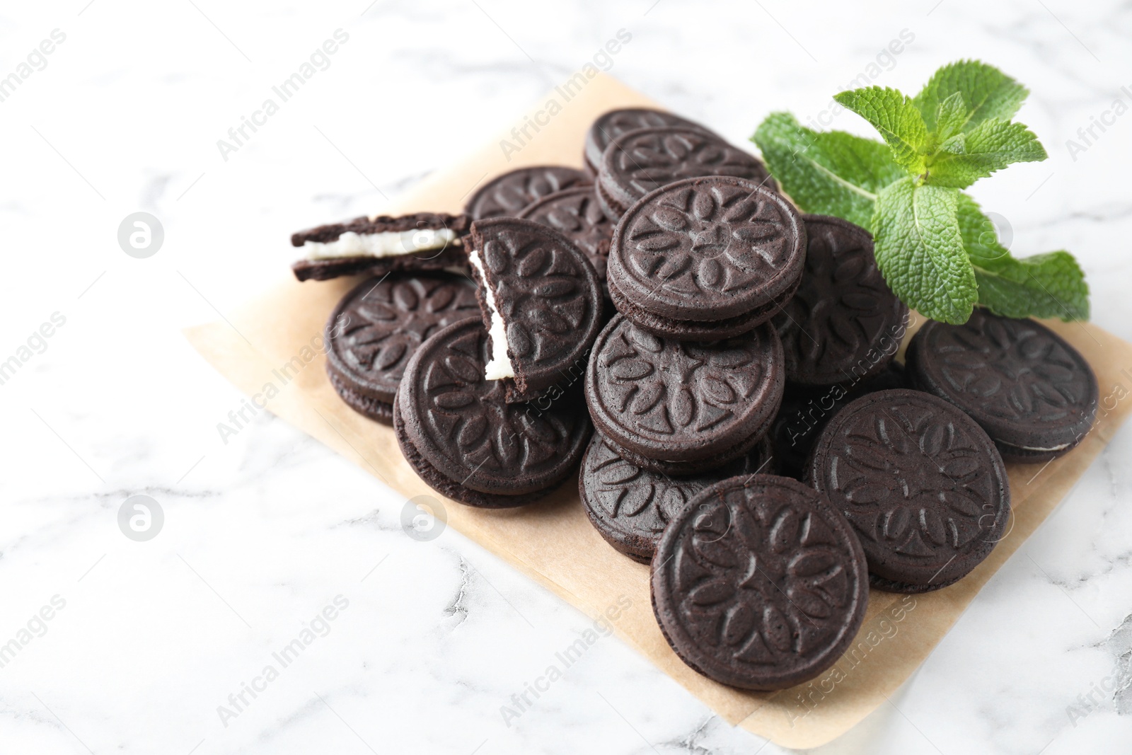 Photo of Tasty sandwich cookies and mint on white marble table