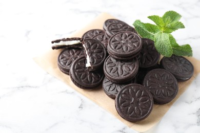 Tasty sandwich cookies and mint on white marble table