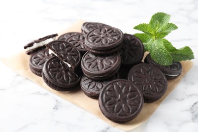 Photo of Tasty sandwich cookies and mint on white marble table