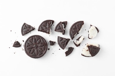 Whole and broken tasty sandwich cookies on white background, flat lay