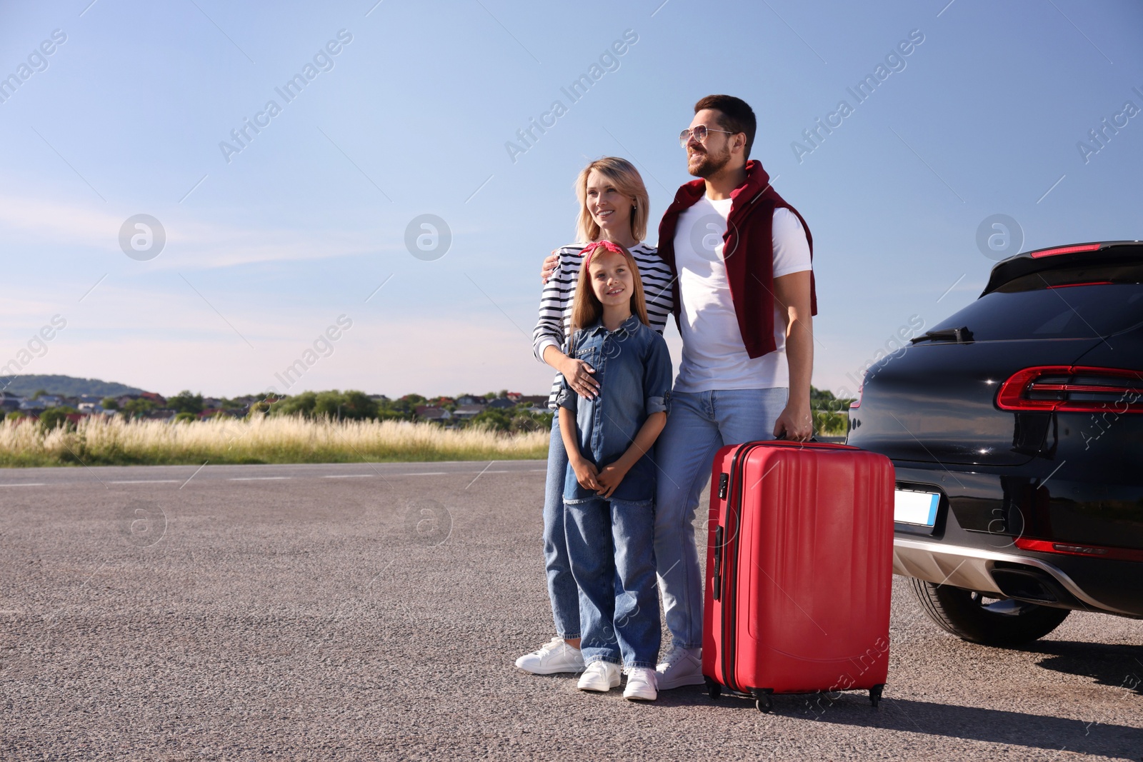 Photo of Happy family with red suitcase near car outdoors, space for text