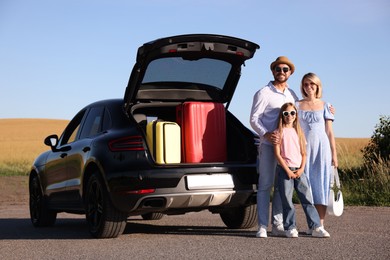 Happy family near car with suitcases outdoors