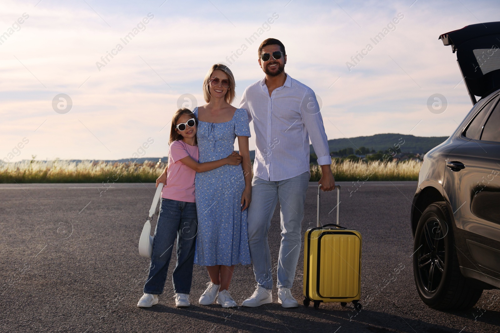 Photo of Happy family with suitcase near car outdoors