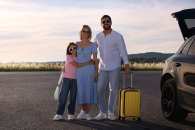 Happy family with suitcase near car outdoors