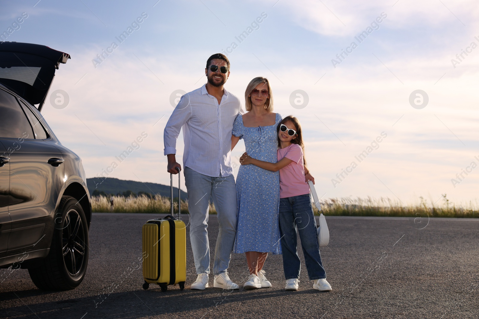 Photo of Happy family with suitcase near car outdoors