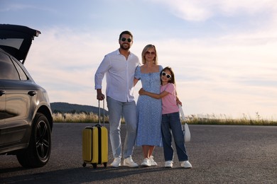 Photo of Happy family with suitcase near car outdoors