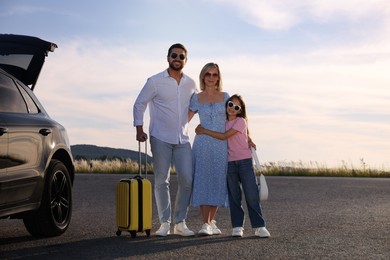 Happy family with suitcase near car outdoors