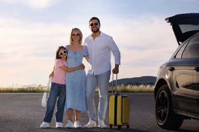 Photo of Happy family with suitcase near car outdoors