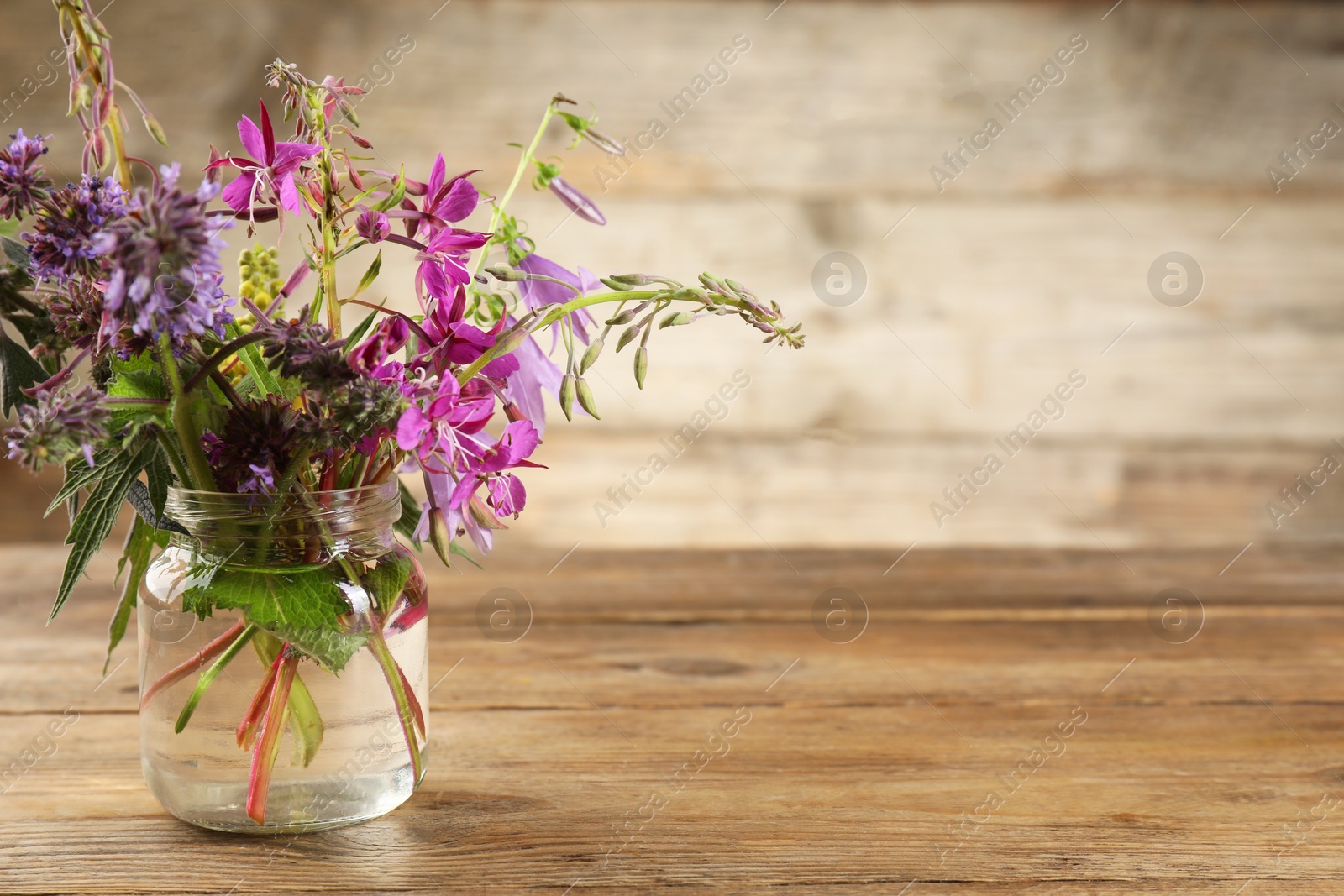 Photo of Bouquet of different healing herbs on wooden table. Space for text