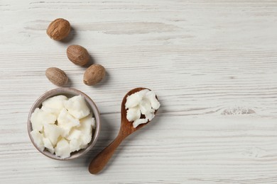 Photo of Shea butter in bowl, spoon and nuts on white wooden table, flat lay. Space for text