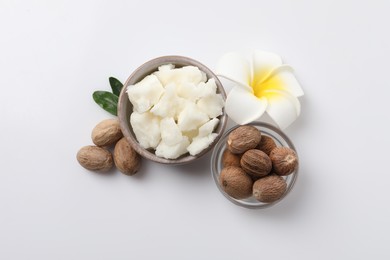 Shea butter in bowl, flower and nuts isolated on white, top view