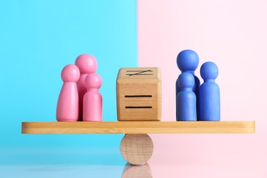 Photo of Gender equality concept. Cube with equals sign between male and female figures on scales against color background