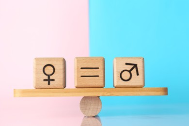 Photo of Gender equality concept. Cubes with male and female symbols on scales against color background