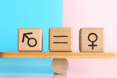 Photo of Gender equality concept. Cubes with male and female symbols on scales against color background