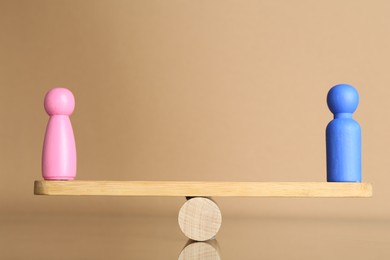 Photo of Gender equality concept. Male and female figures on scales against beige background