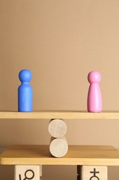 Photo of Gender equality concept. Male and female figures on scales against beige background