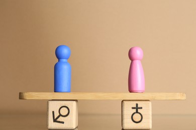 Photo of Gender equality concept. Male and female figures on scales against beige background