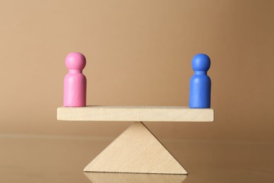 Photo of Gender equality concept. Male and female figures on scales against beige background