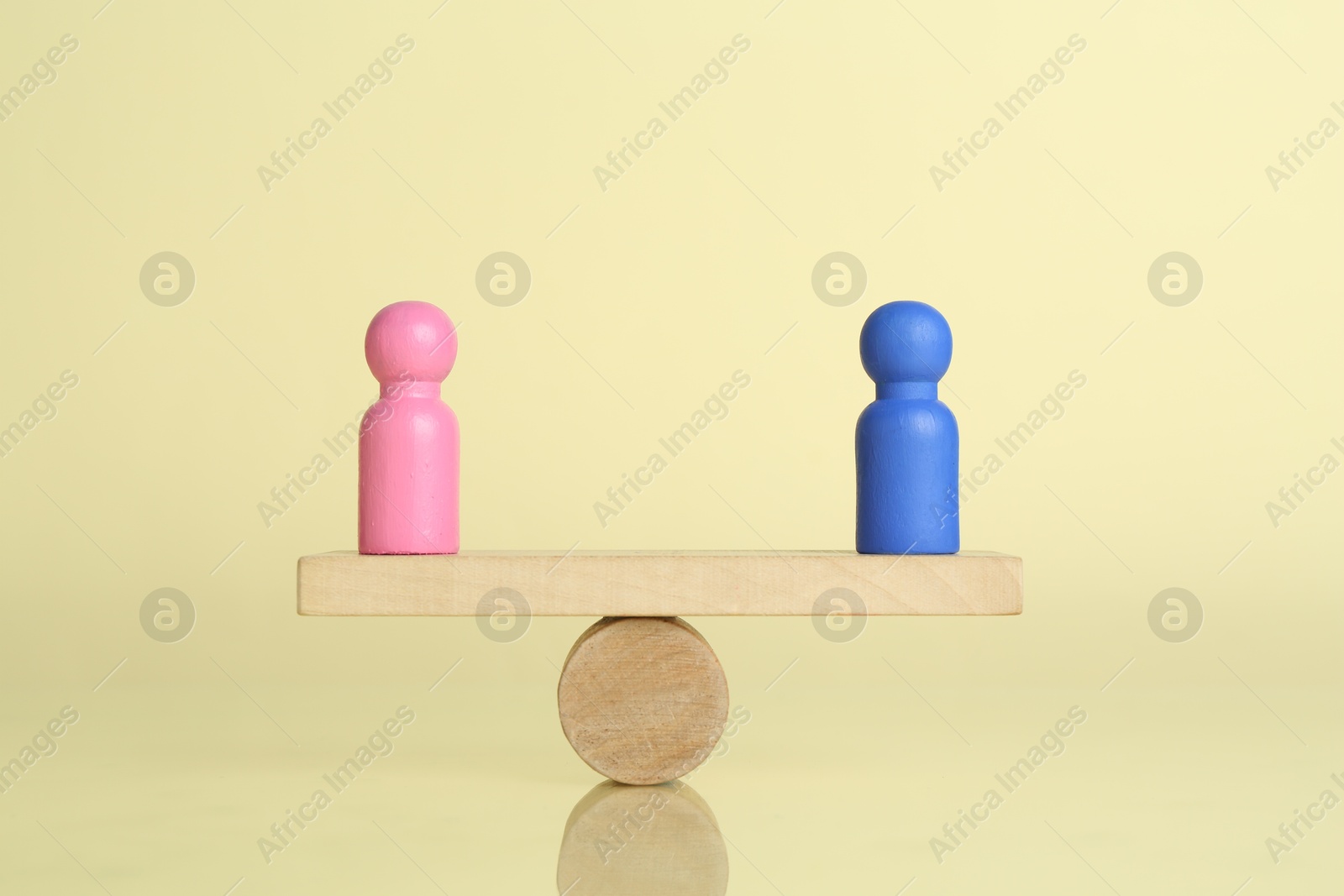 Photo of Gender equality concept. Male and female figures on scales against light yellow background