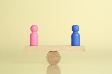 Photo of Gender equality concept. Male and female figures on scales against light yellow background