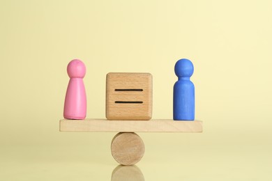 Photo of Gender equality concept. Cube with equals sign between male and female figures on scales against light yellow background