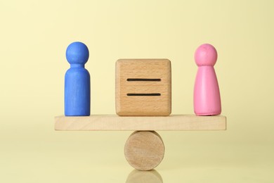 Photo of Gender equality concept. Cube with equals sign between male and female figures on scales against light yellow background