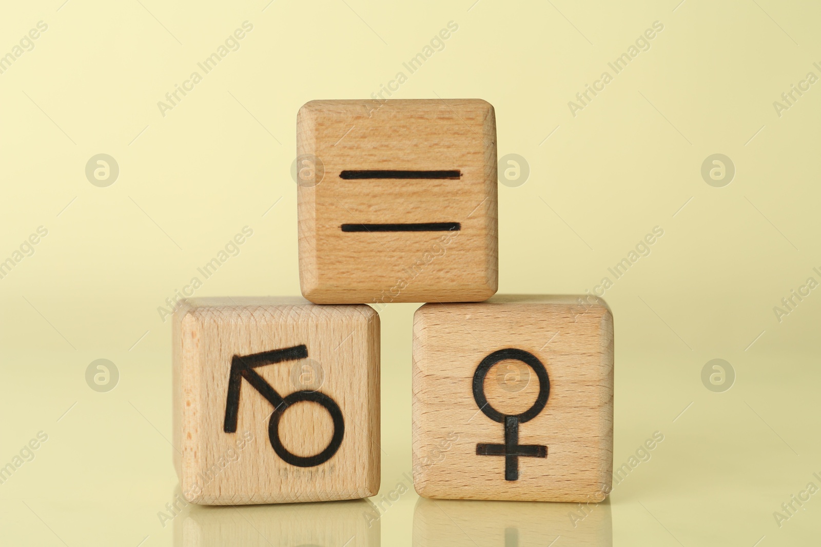 Photo of Gender equality concept. Wooden cubes with male and female symbols on light yellow background