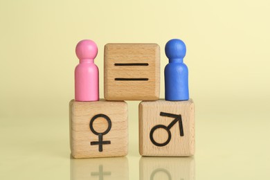 Gender equality concept. Wooden cubes with male and female figures on light yellow background