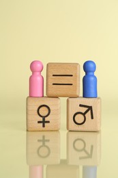 Gender equality concept. Wooden cubes with male and female figures on light yellow background