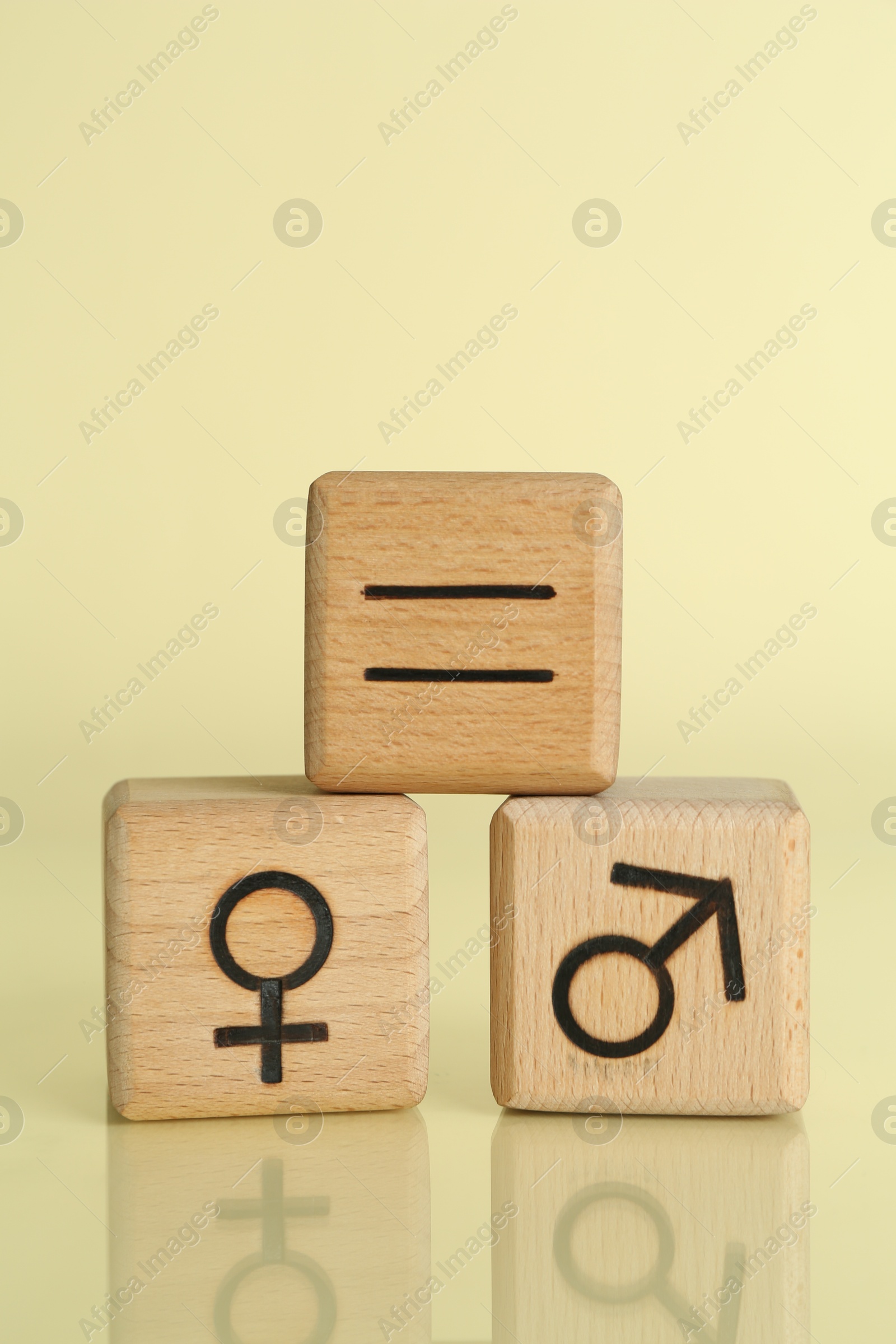 Photo of Gender equality concept. Wooden cubes with male and female symbols on light yellow background