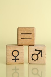 Gender equality concept. Wooden cubes with male and female symbols on light yellow background