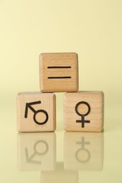 Photo of Gender equality concept. Wooden cubes with male and female symbols on light yellow background