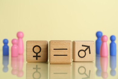 Gender equality concept. Wooden cubes with male and female symbols on light yellow background