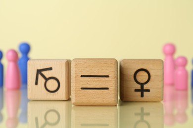 Photo of Gender equality concept. Wooden cubes with male and female symbols on light yellow background